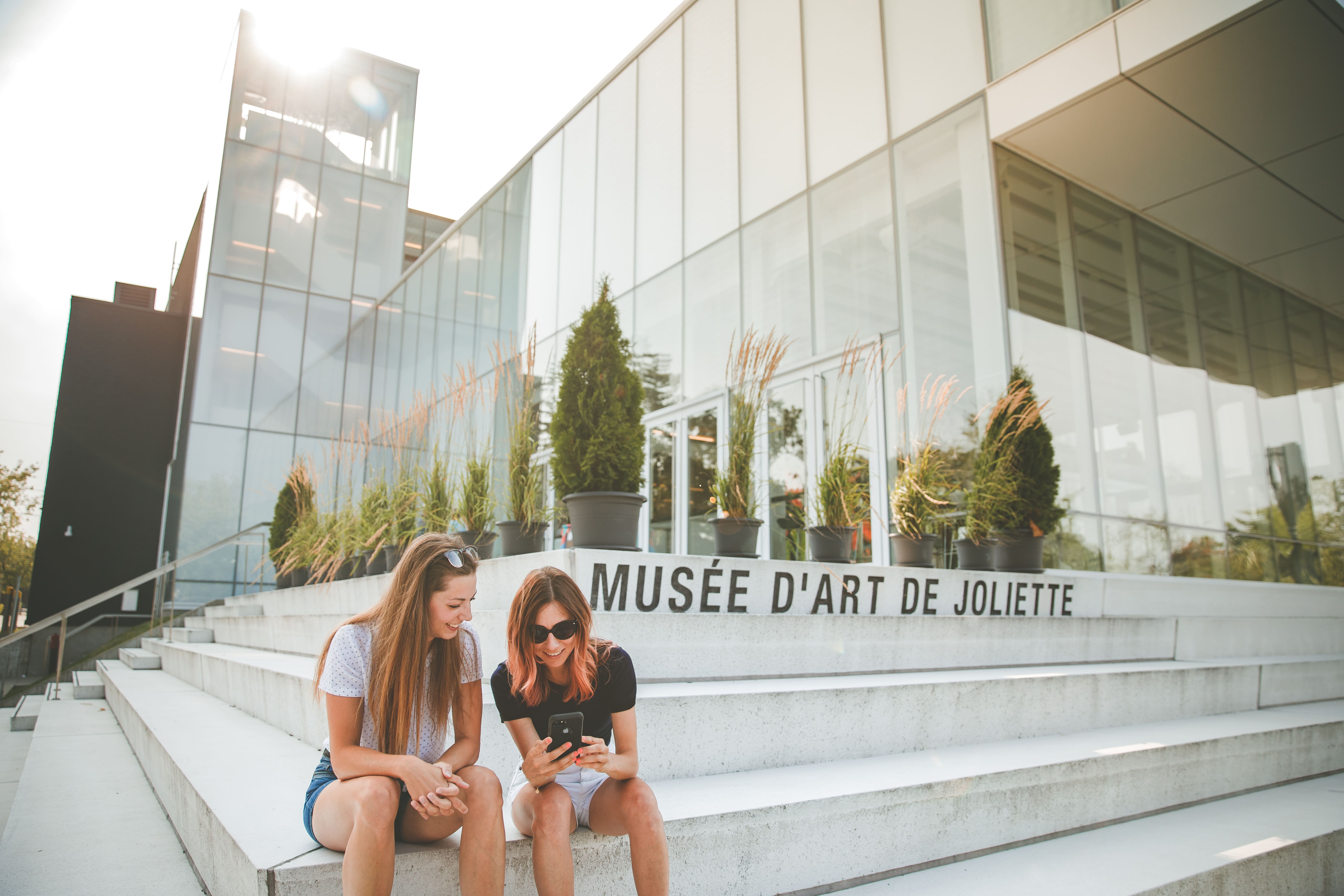 2 femmes assises sur des escaliers devant le Musée d'art de Joliette