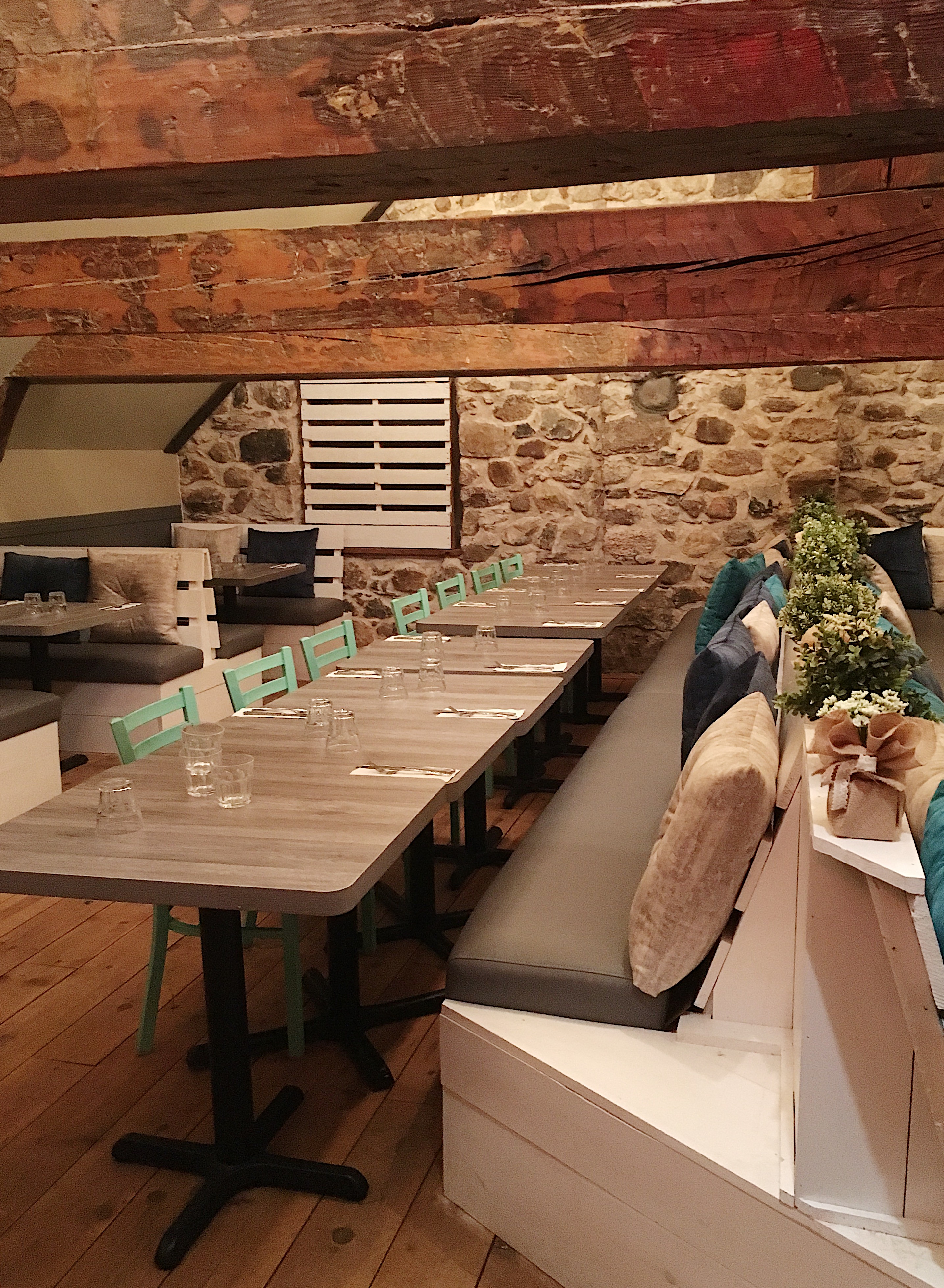 Salle privée du restaurant le Vice-Caché avec poutre en bois et mur de pierre